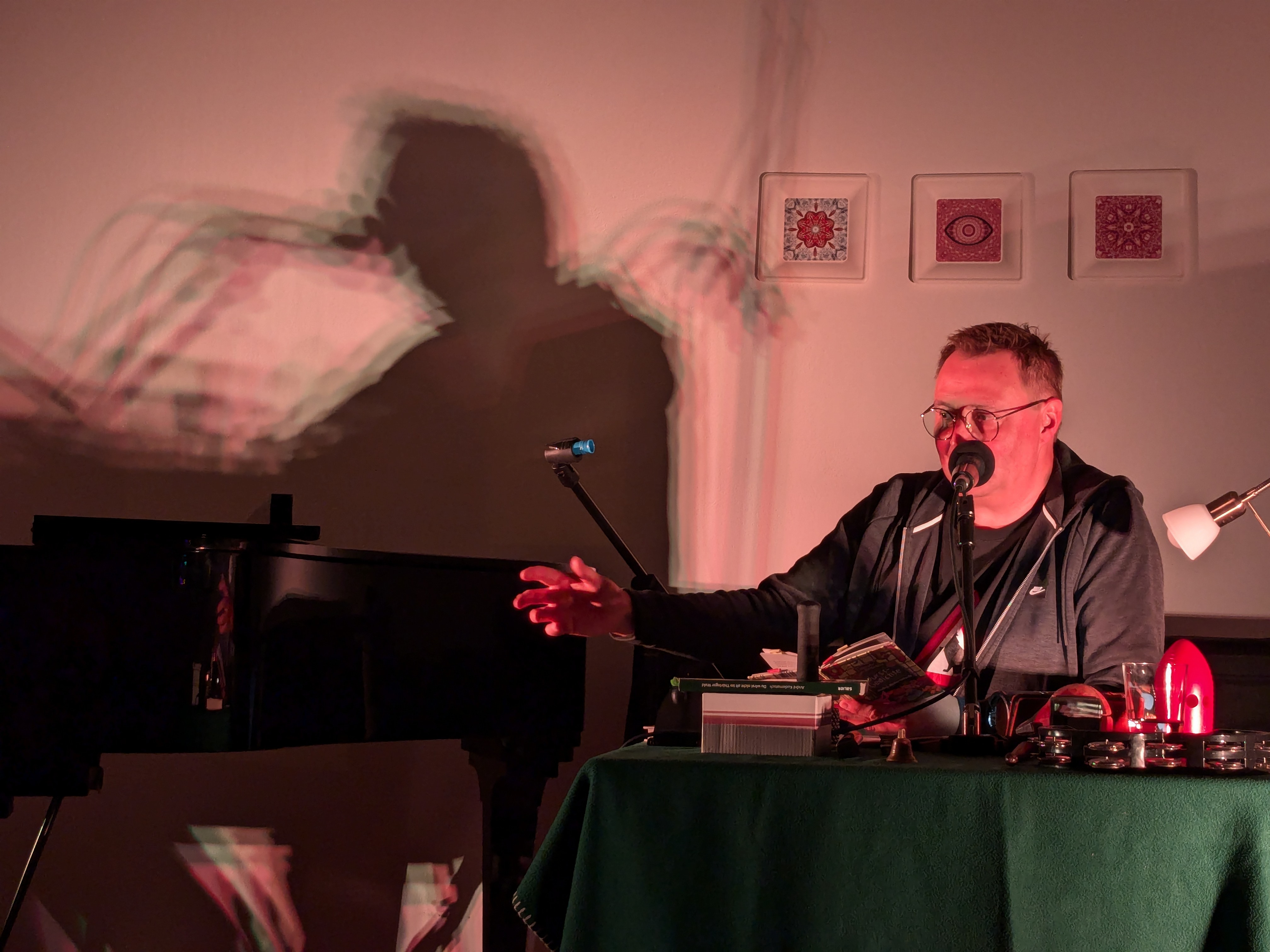 Andre Kudernatsch sitzt am Tisch mit einem Mikrofon vor dem Mund. Im Hintergrund sind Wurstbilder zu sehen.